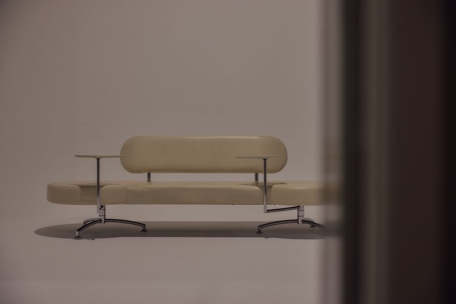 Cream leather bench with chrome legs on the white cove.