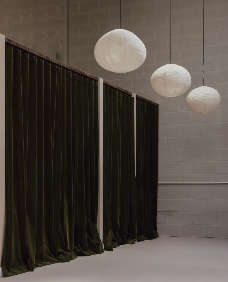 Olive velvet curtain bays beneath glowing paper lanterns.