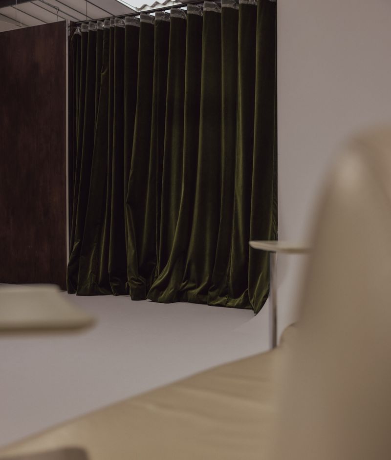 Olive velvet curtain seen past cream leather seating.