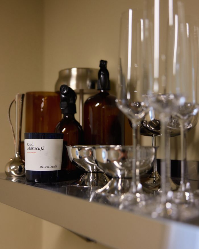 Glassware and bottles on the kitchenette shelf above the steel sink.
