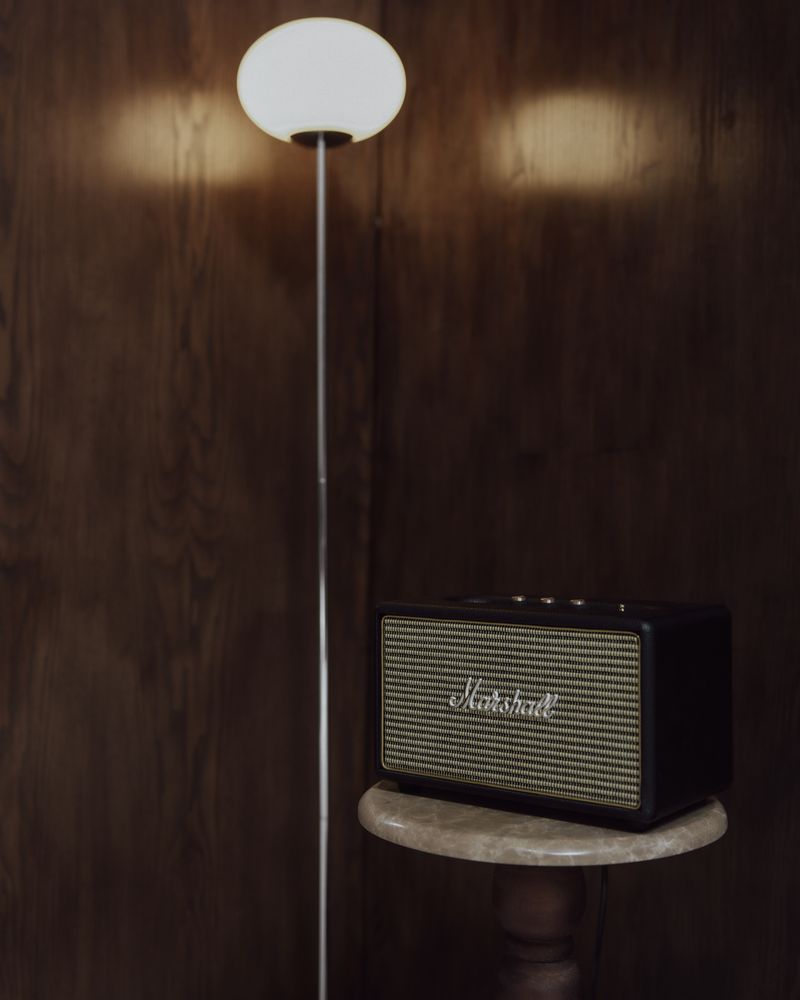 Warm lamp light and a speaker in the walnut corner.